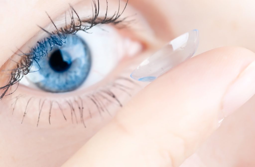 Close up of women with blue eyes putting in contact lenses