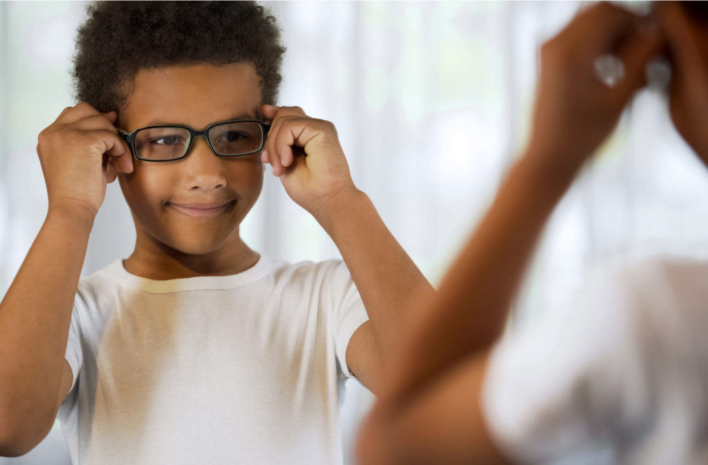 Young boy looking in mirror trying out his new glasses