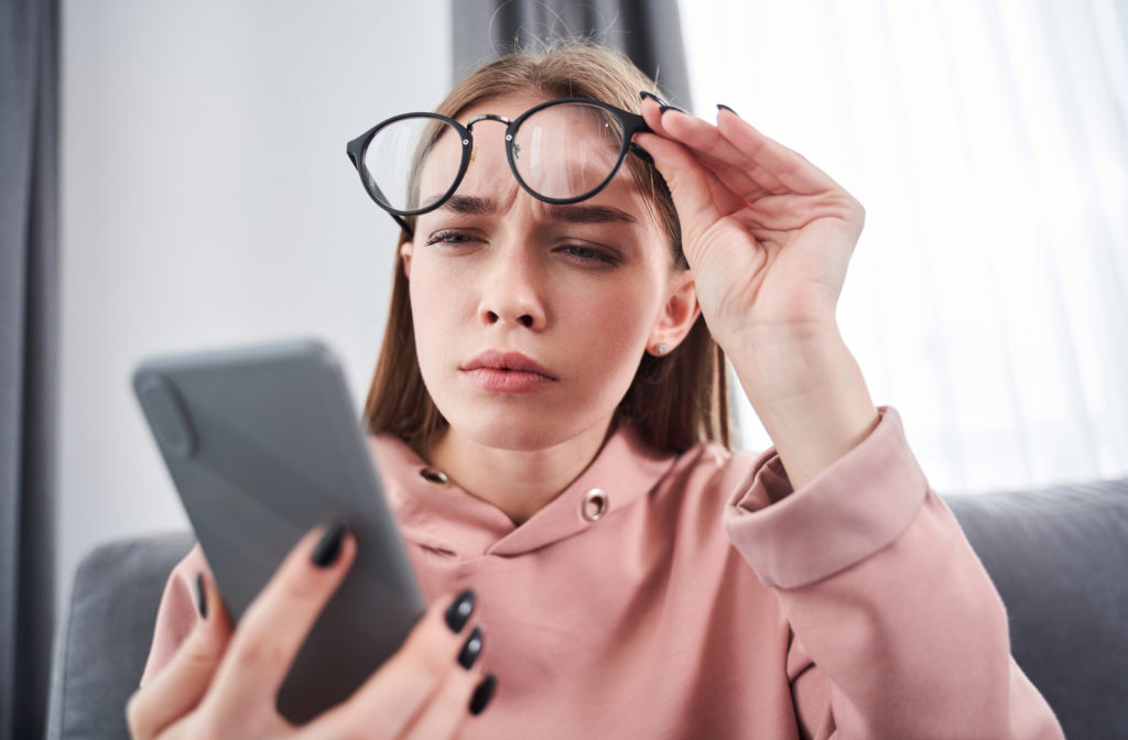 Young girl squinting to see what is on her phone