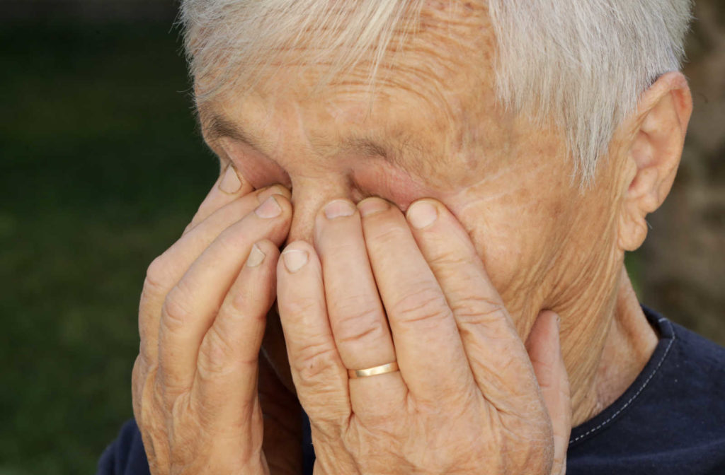 A senior lady is rubbing her dry eyes to comfort the itchiness inside her eye.