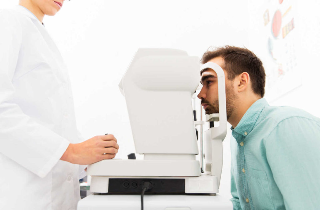 A close-up of an optometrist with an autorefractor checking a male patient's vision.