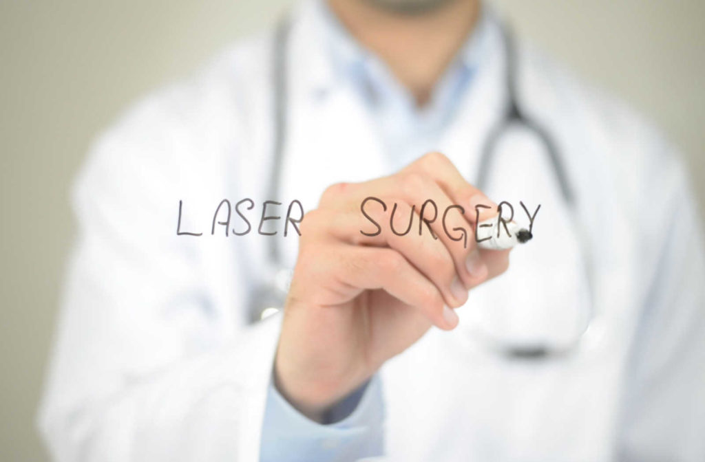 A doctor writing laser surgery with a marker on glass.
