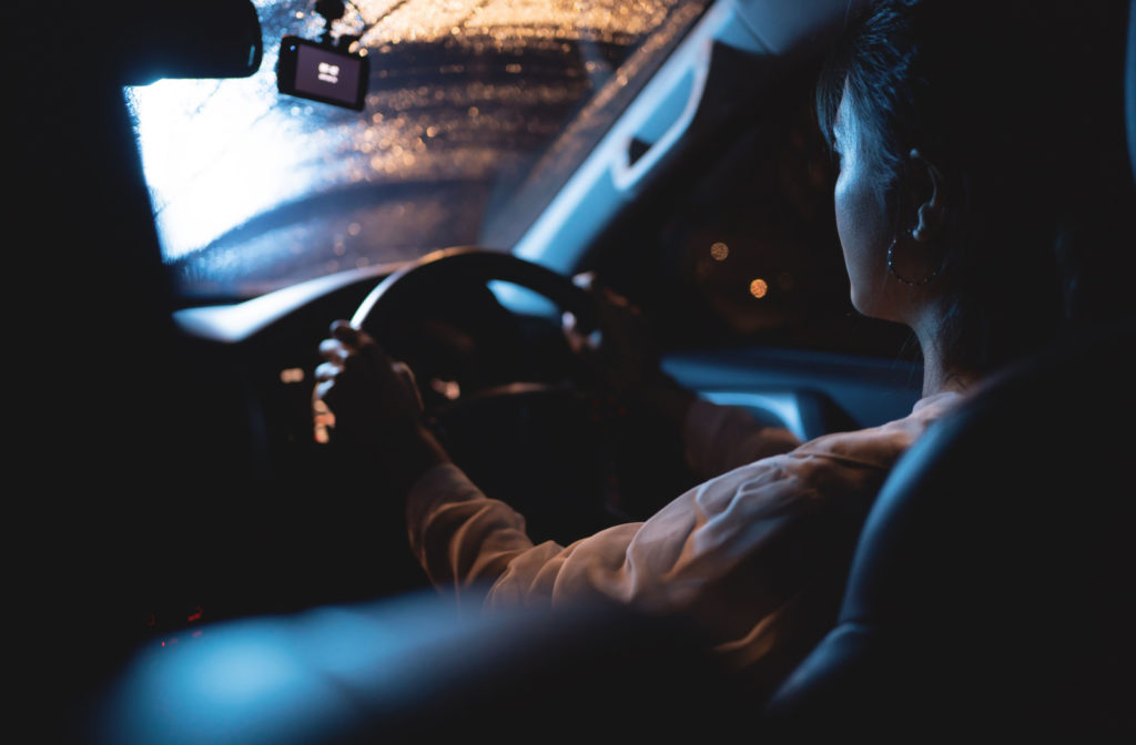 A woman driving on a rainy night.