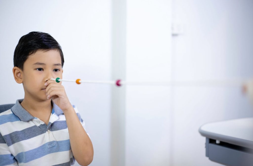 A child in a striped blue polo using a Brock string to do vision convergence training in vision therapy