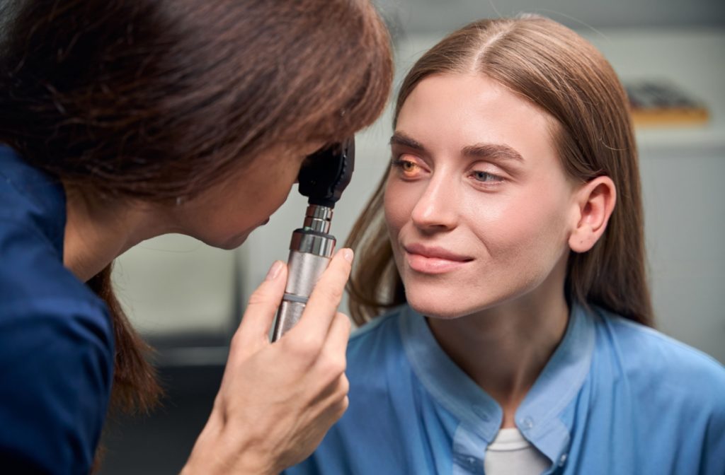 An optometrist looking through a retinoscope at a patient's left eye to check for signs of a retinal detachment.