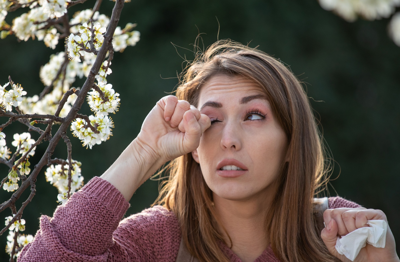 A person suffering from seasonal allergies rubbing their irritated dry eyes.