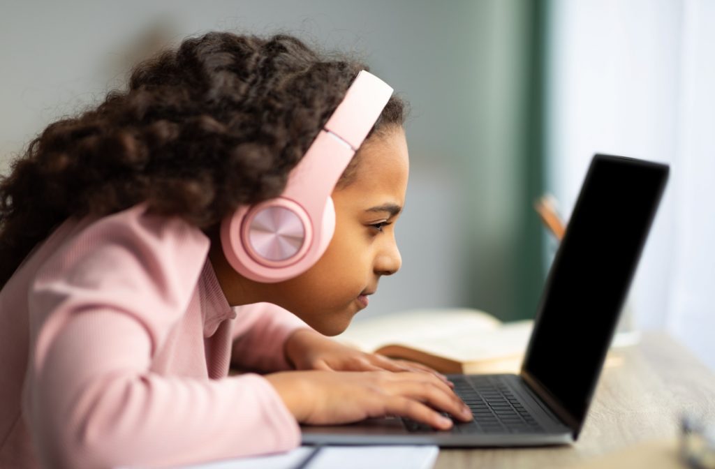 Young girl looking up close at a laptop screen.